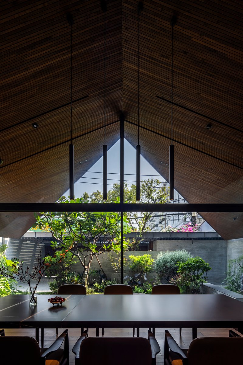 Dining table beneath gabled window overlooking an internal courtyard with trees and flowering plants