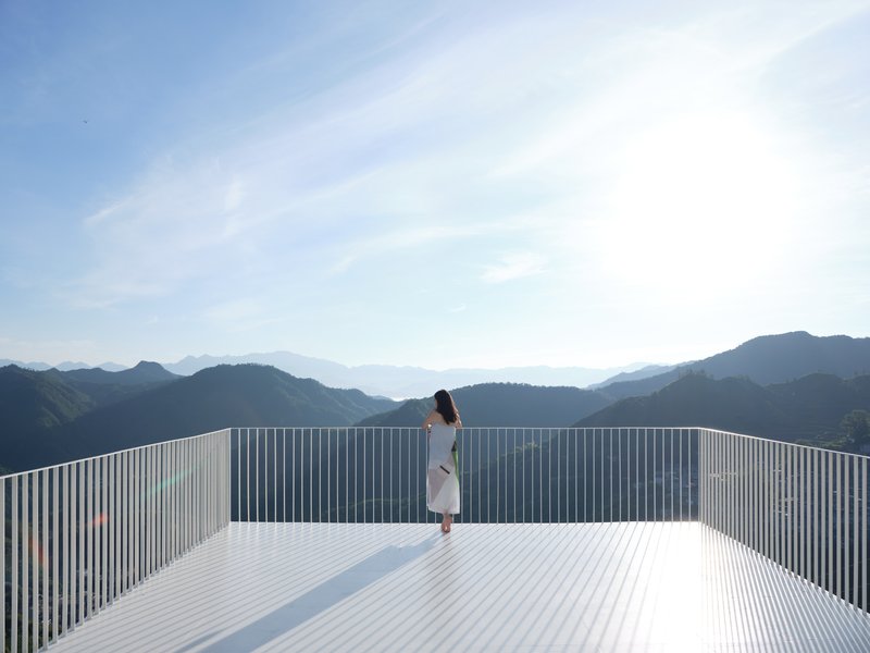 Rooftop terrace with vertical metal louvers overlooking a mountain range on a clear day