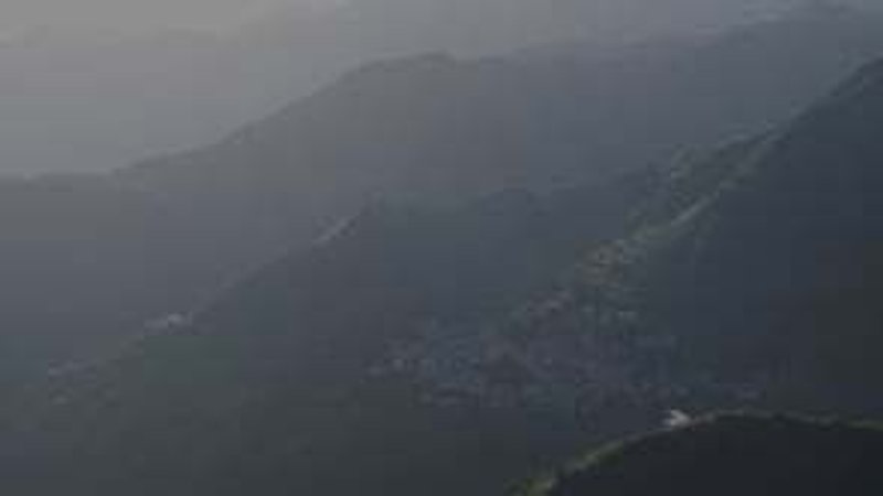 Distant view of the white-roofed structure in heavy mountain mist