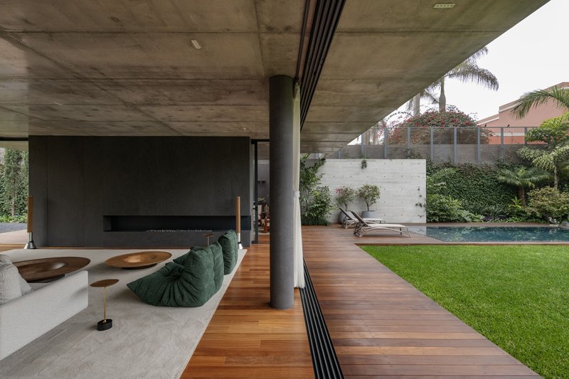 Covered terrace with timber decking extending toward the pool and lawn beyond concrete columns