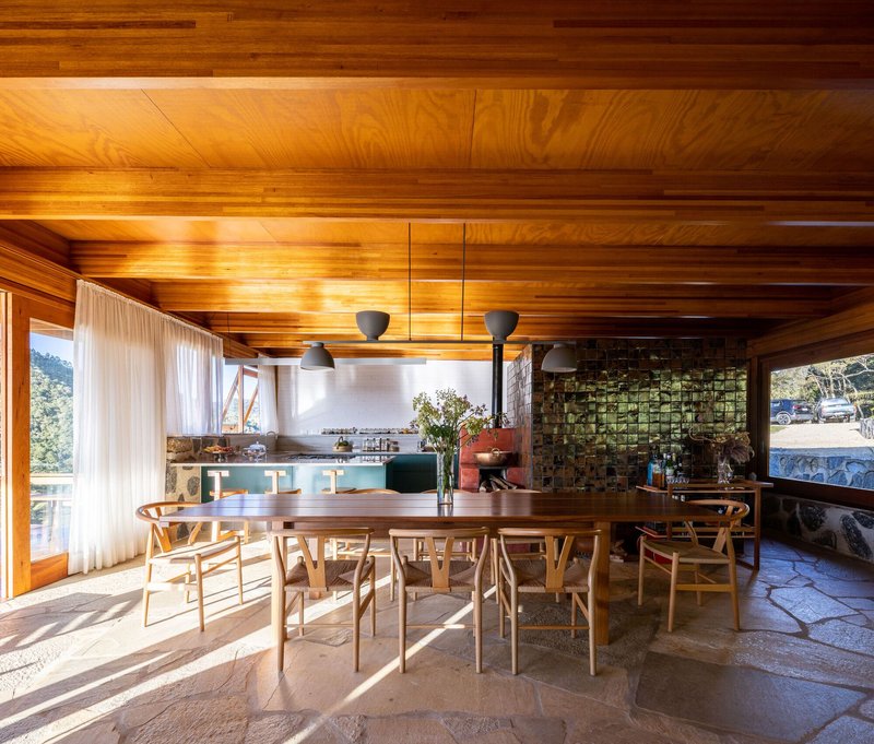 Dining area with timber ceiling beams and irregular stone floor illuminated by morning sunlight