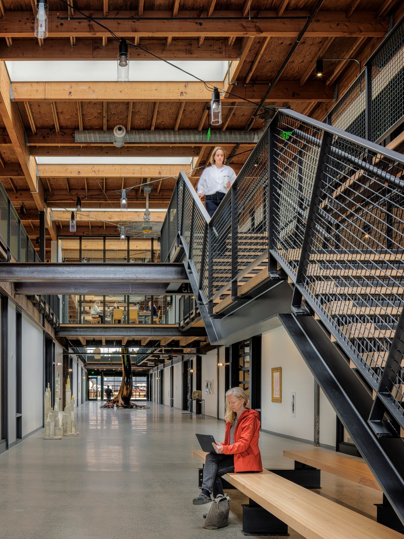 Interior atrium with exposed timber joists, steel mesh railings, and skylights overhead