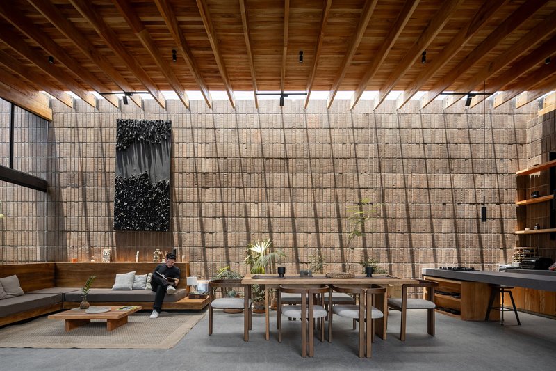 Interior living space with gridded concrete block wall and timber beam ceiling under diffused daylight