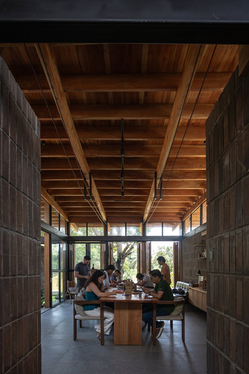 Dining area with timber-clad walls and exposed ceiling joists, family gathered around a central table at dusk