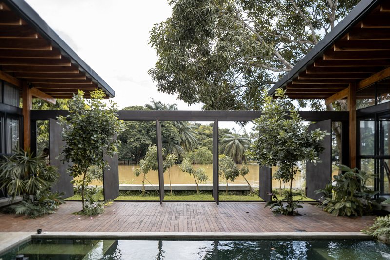 Courtyard with swimming pool and timber deck beneath twin timber-roofed pavilions and planted steel frame screens