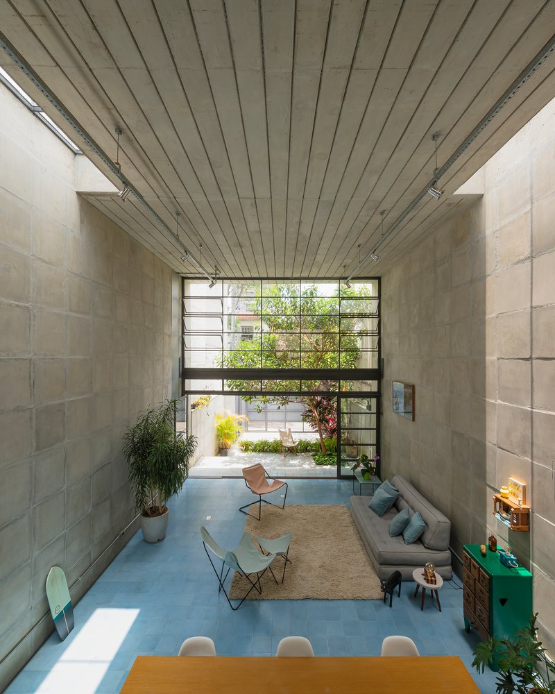 View through double-height space toward steel-framed window wall with courtyard garden beyond