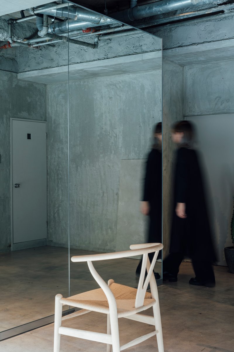 Single wooden chair behind glass panel with two figures in motion blur passing by