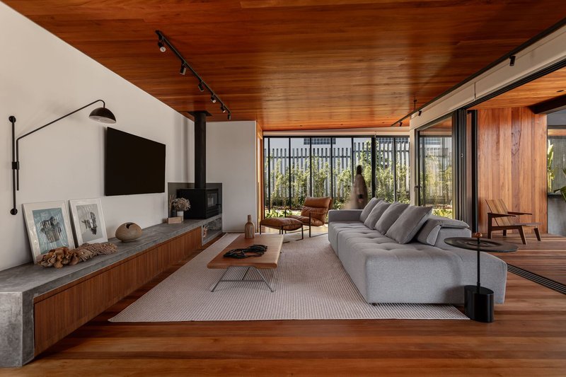 Living room with timber ceiling and concrete media console overlooking a vertical timber screen garden