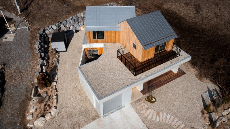 Aerial view of the residence showing gabled roofs, gravel terrace and stone retaining walls