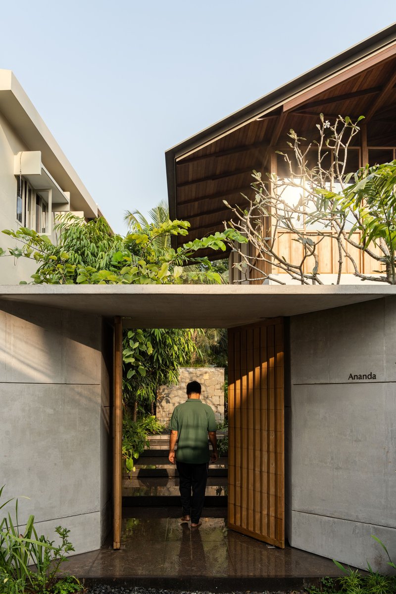 Entry threshold with timber-lined gateway and person walking toward interior courtyard staircase