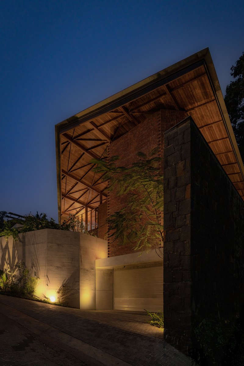 Street elevation showing brick facade with exposed timber roof structure and concrete lower level at dusk