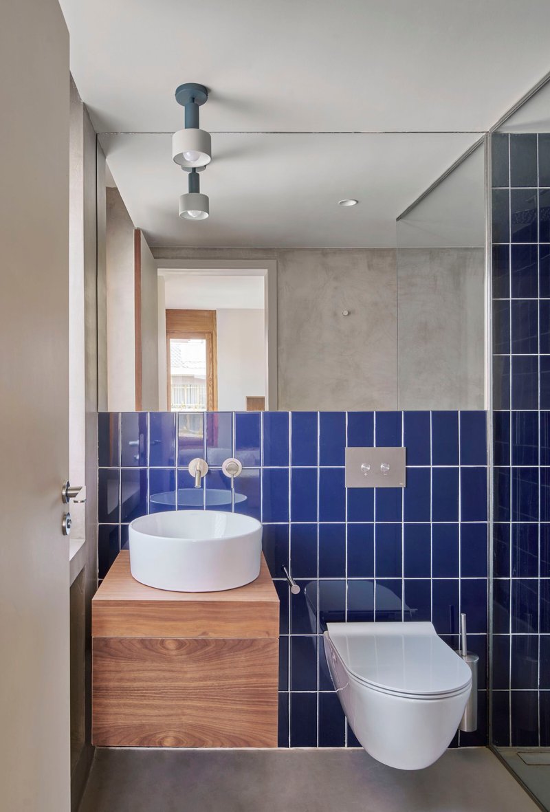 Compact bathroom with cobalt blue square tiles and a round vessel sink on timber vanity