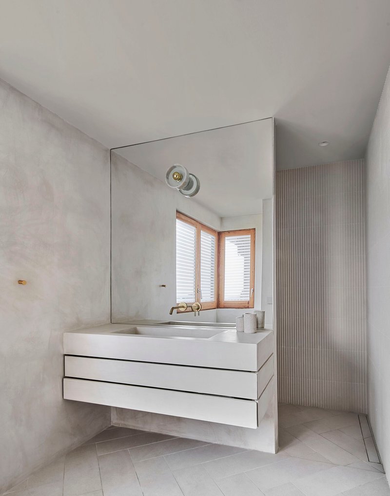 Floating white vanity with integrated sink beneath a large mirror and textured grey plaster walls