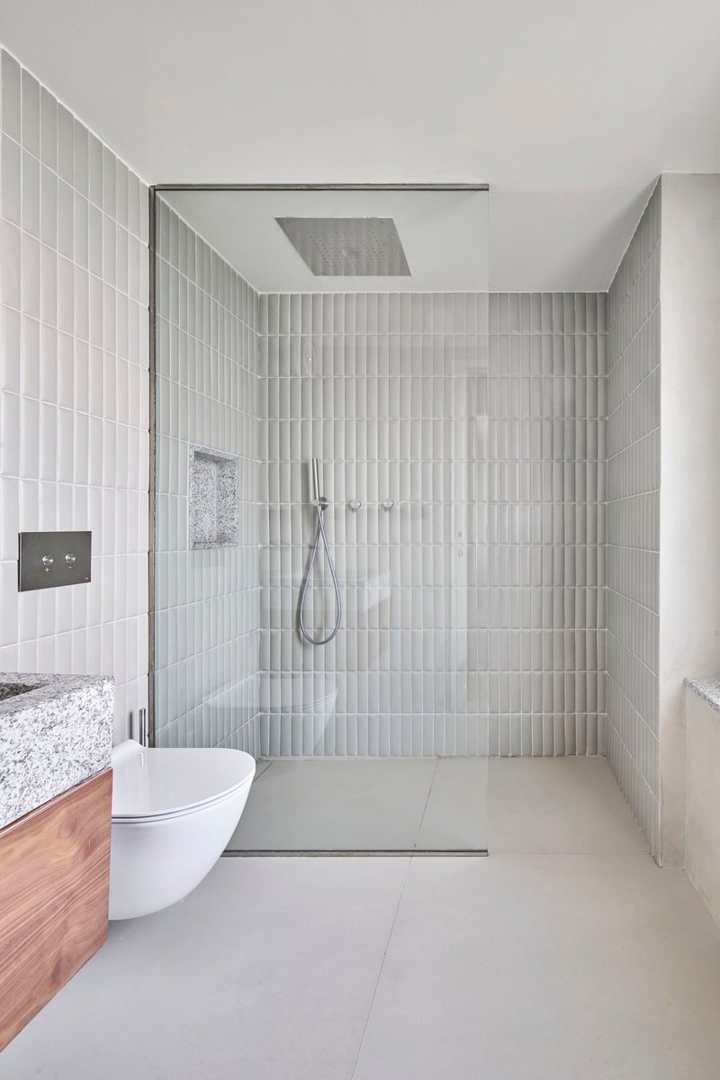 Glass-enclosed shower with vertical white tile walls and ceiling-mounted rainfall showerhead