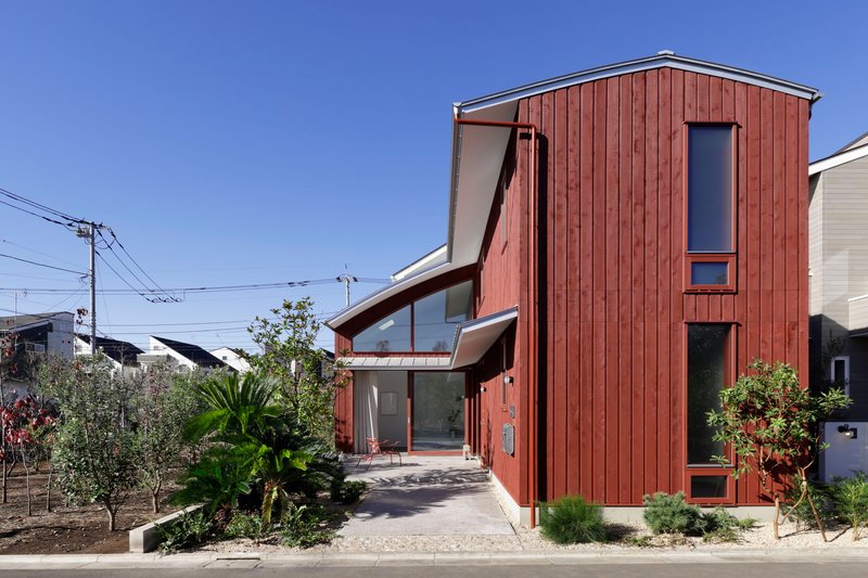 Street view of the vertical timber-clad volume with garden beds and overhead power lines