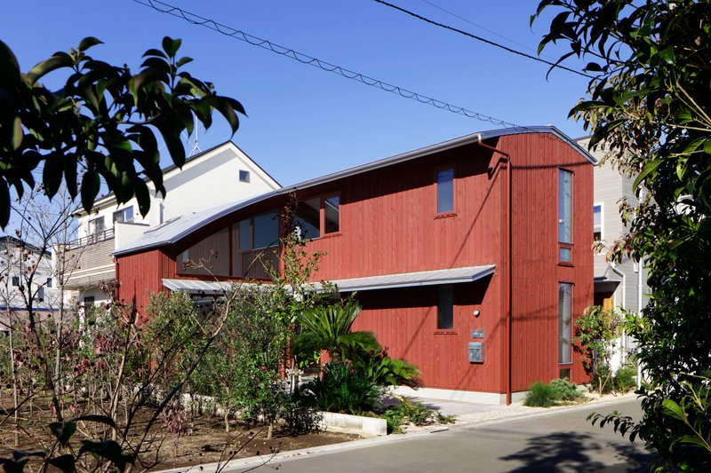 Side elevation showing the curved roof connecting the two-story timber volumes among bare winter trees