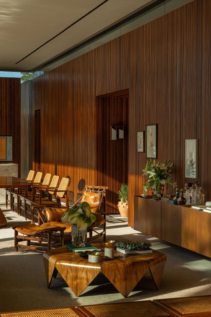 Living room with vertical timber wall panels illuminated by afternoon sunlight through floor-to-ceiling glass