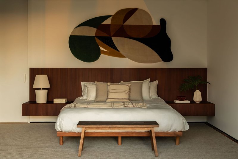 Bedroom with integrated timber headboard wall beneath a geometric abstract painting in warm tones
