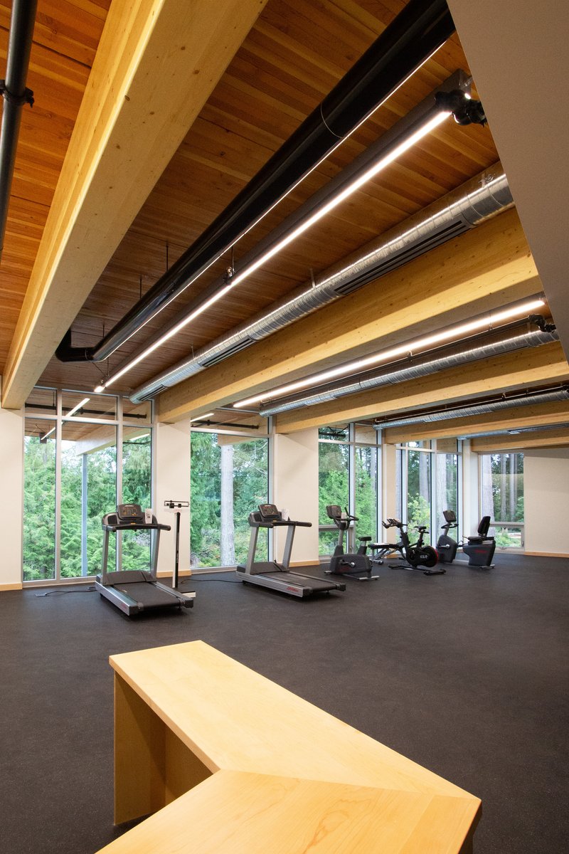 Fitness room with exposed timber ceiling joists, linear lighting, and treadmills along the glazed wall