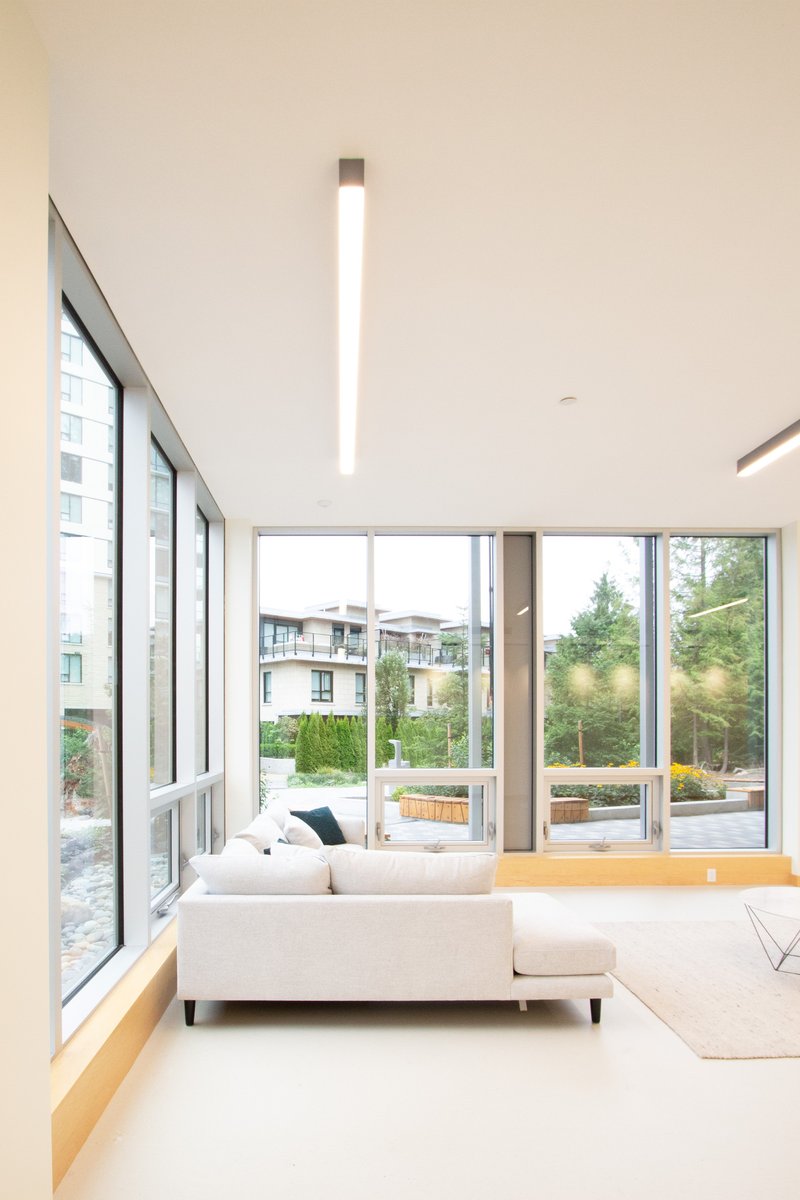 Double-height lounge with sloped ceiling, glazed walls, and a suspended linear pendant fixture
