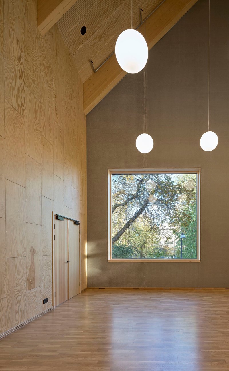 Double-height room with pendant lights and square window framing a bare tree outside