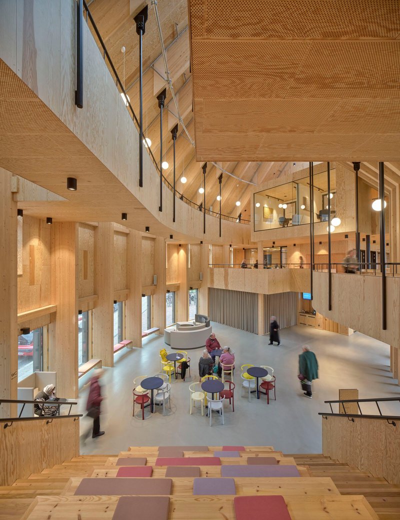 Multi-level interior atrium with timber walls, suspended globe lights, and visitors seated below