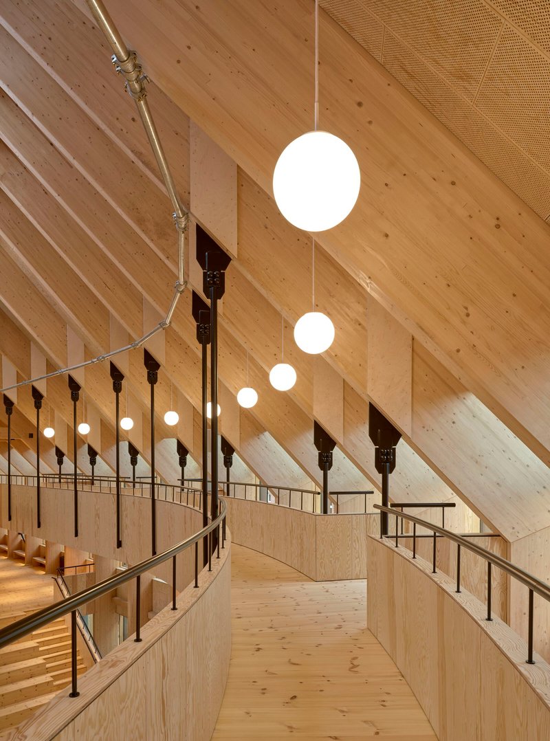 Narrow walkway along the upper gallery with cable railings and pendant lights beneath the angled timber ceiling