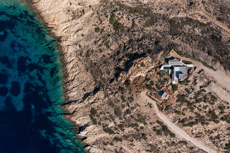 Aerial view of the stone and concrete structures nestled into rocky coastal terrain above turquoise water
