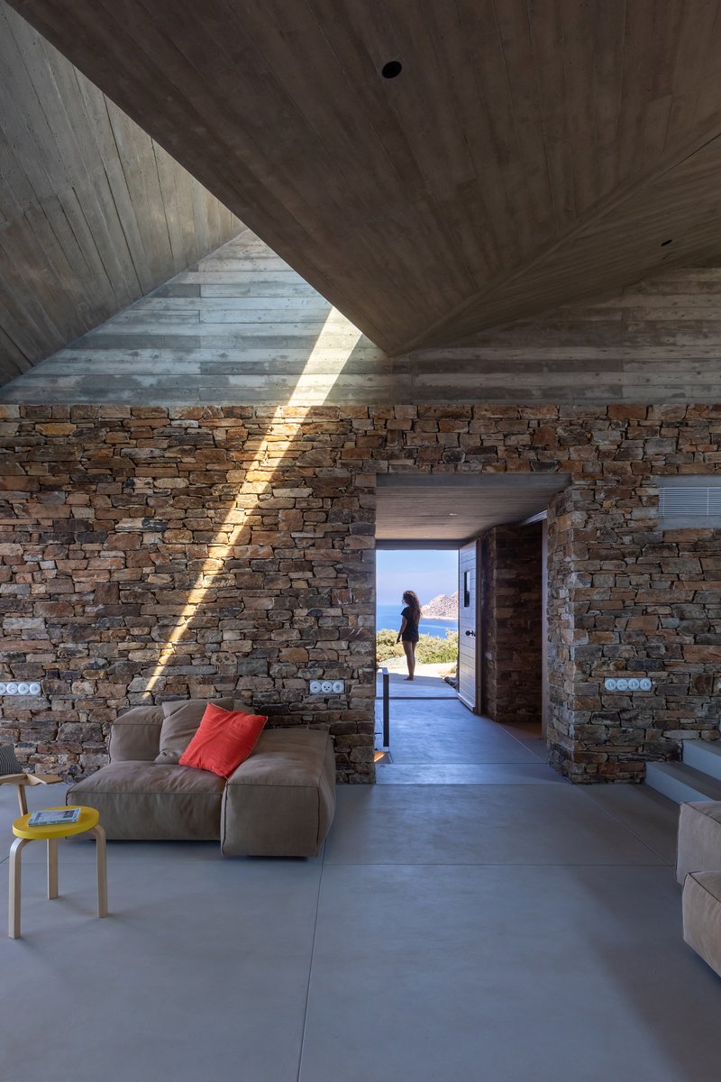 Stone partition wall with vertical skylight slot casting a blade of light across the interior