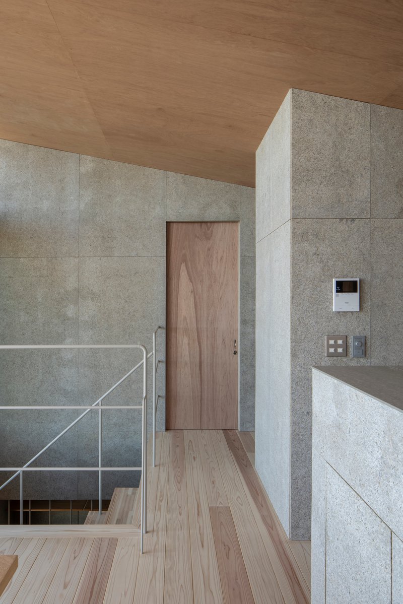 Upper level landing with concrete panel walls, timber door and ceiling, and steel stair railing