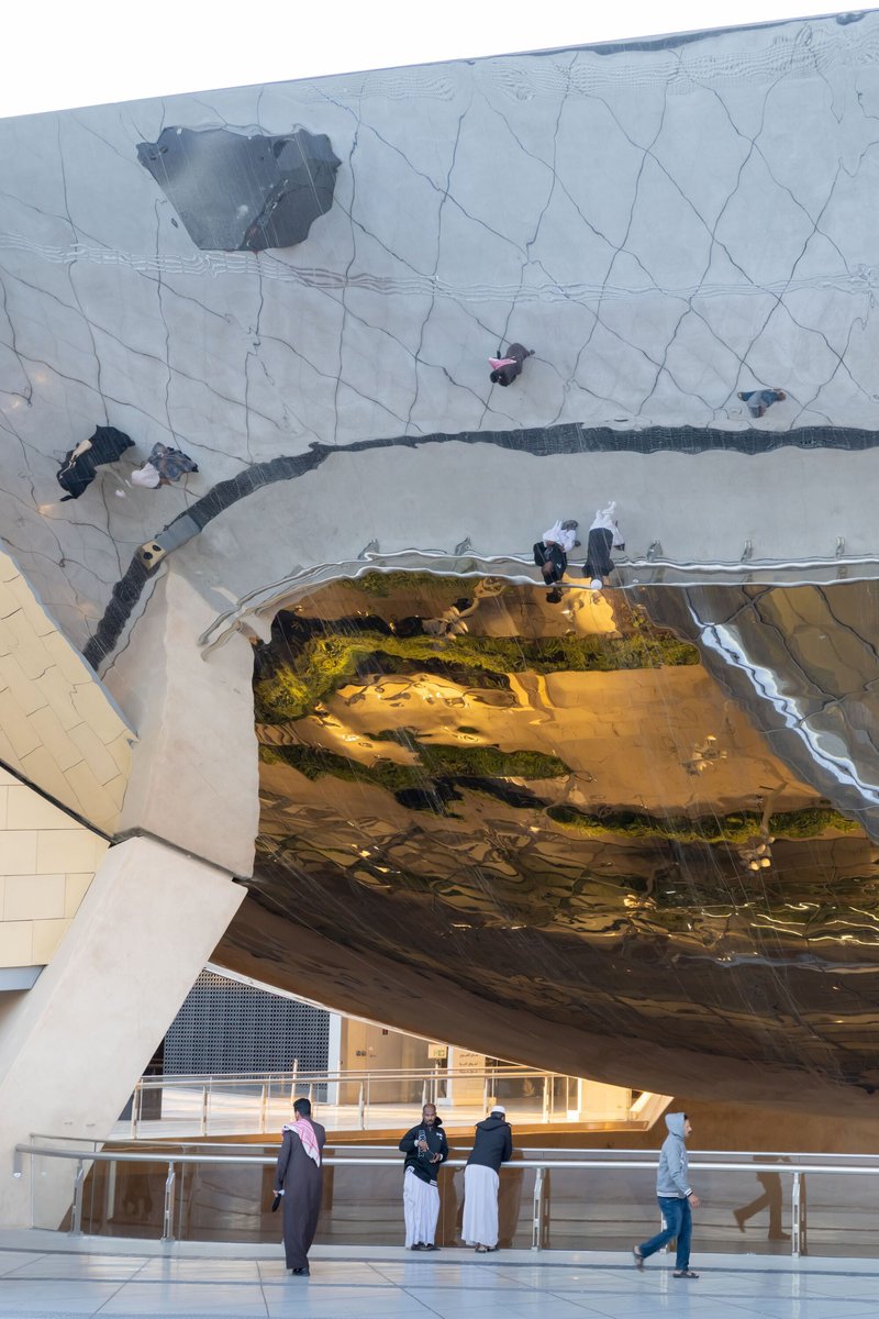 Underside of the reflective metal canopy mirroring visitors and surrounding landscape on the polished surface