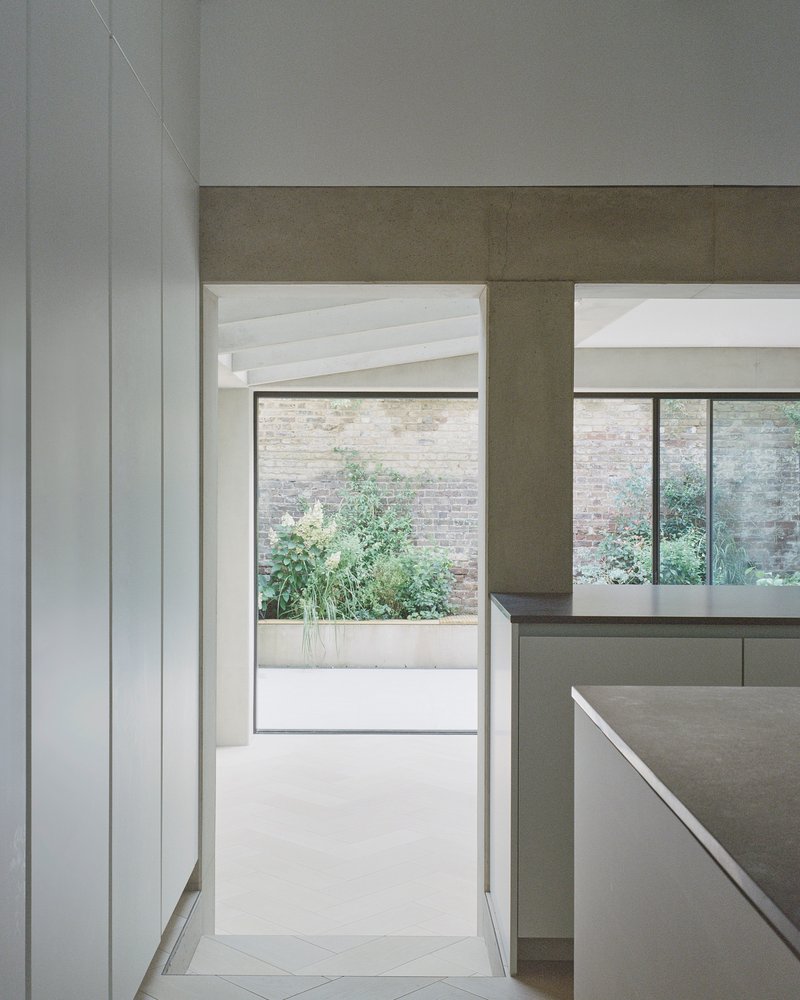 View through kitchen toward courtyard with planted greenery beyond glass doors