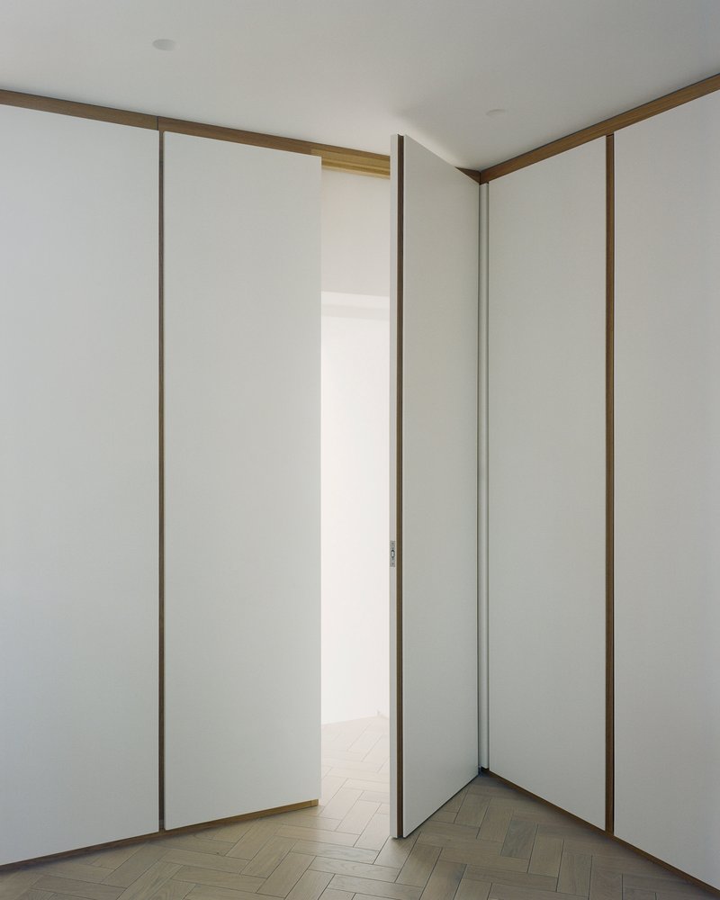 Corner of white room with floor-to-ceiling sliding panels framed in timber edging