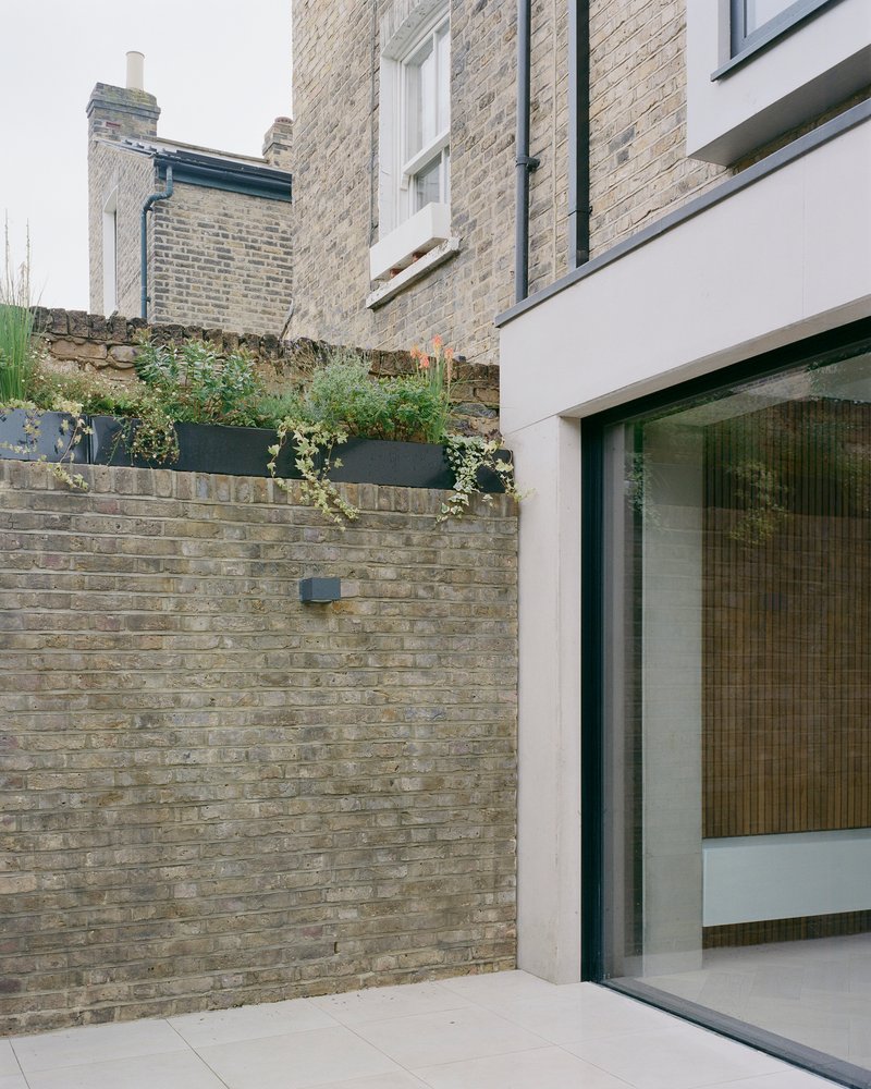 Rear courtyard with weathered brick boundary wall and planted metal planter boxes