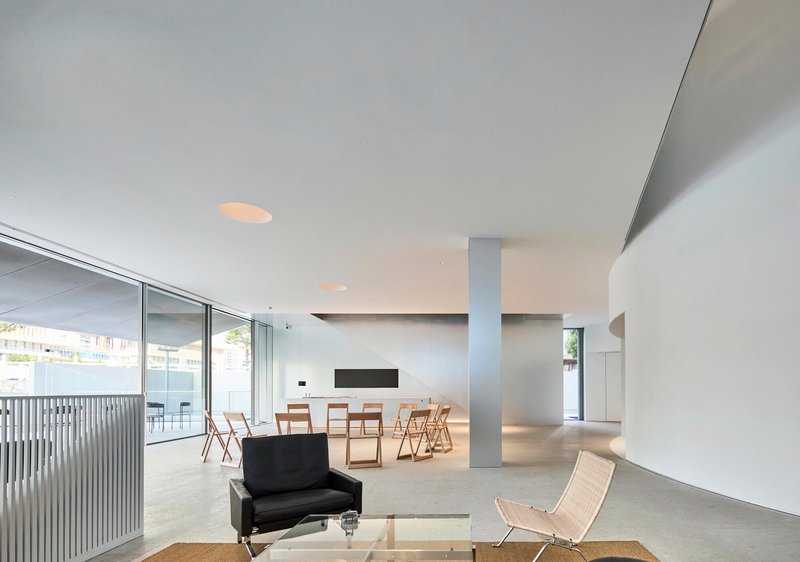 Open-plan interior with white ceiling, terrazzo flooring and full-height glazing opening to a terrace