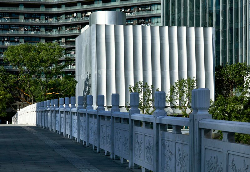 White cylindrical columns rising behind ornamental stone railing with carved panels and balusters