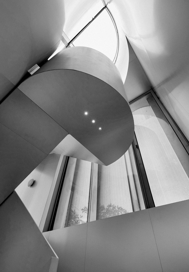 Upward view of a curved balcony edge wrapping around a multi-story atrium with skylights above