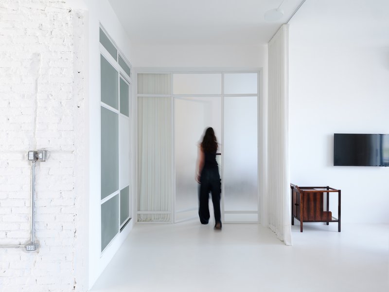 Hallway view showing painted brick wall and figure standing by frosted glass doors