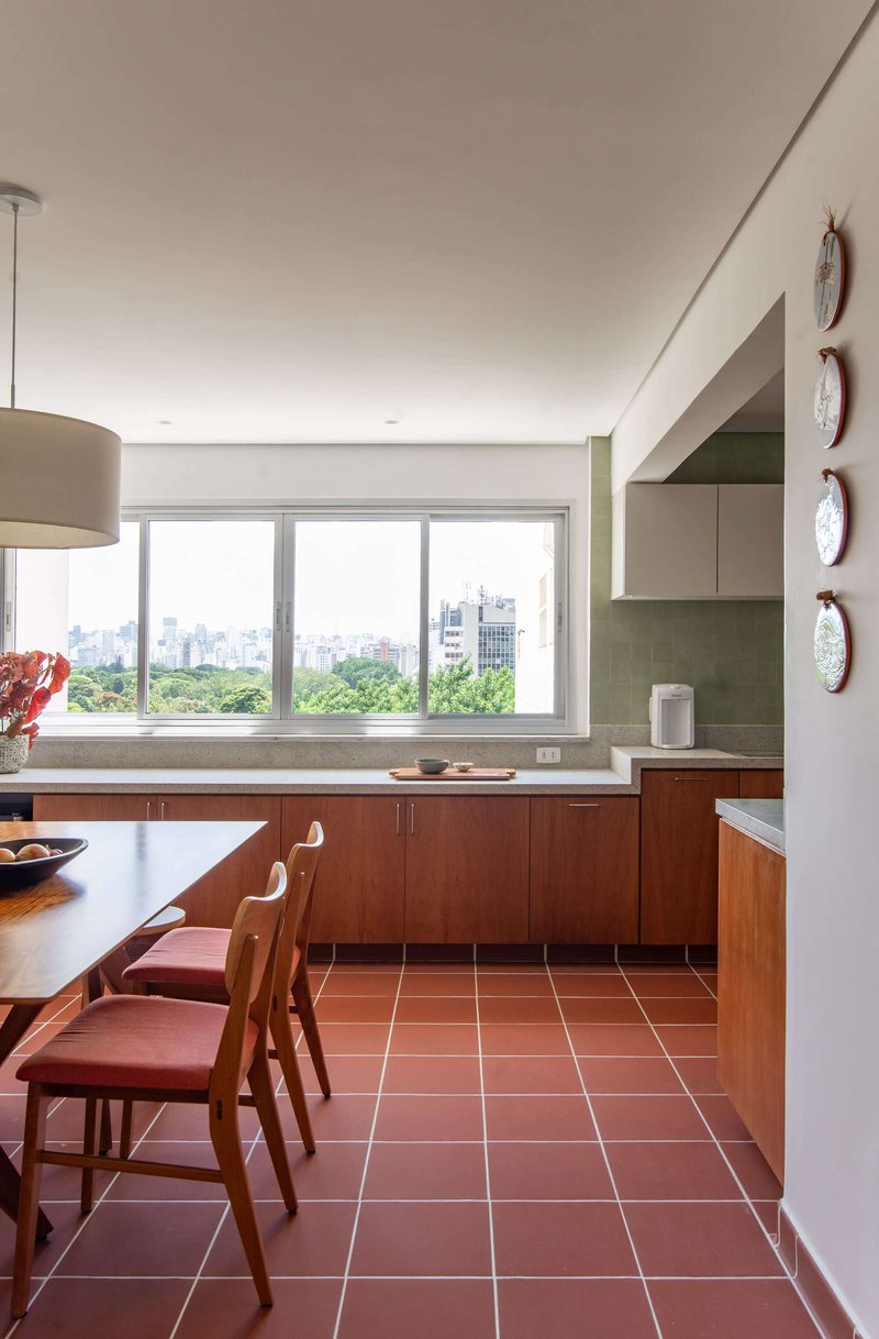 Kitchen with terracotta tile floor, wood cabinetry and a wide window framing treetops and distant towers
