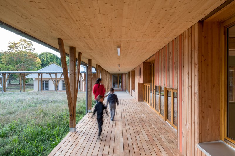Covered timber walkway with diagonal wood braces and two children running on the decking