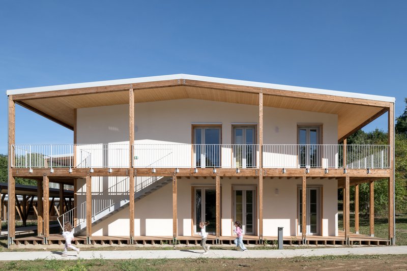Two-storey timber structure with exposed wooden columns and elevated walkway under a clear blue sky