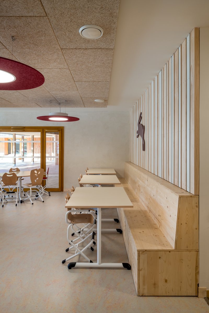 Classroom with maroon disc pendant lights above built-in timber benches and vertical slat wall panel