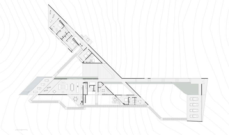 Floor plan drawing showing two angular wings intersecting at a central core with topographic contours