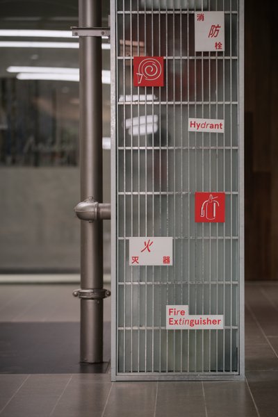 The image showcases a fire safety station with a metal grate enclosure, prominently displaying signa