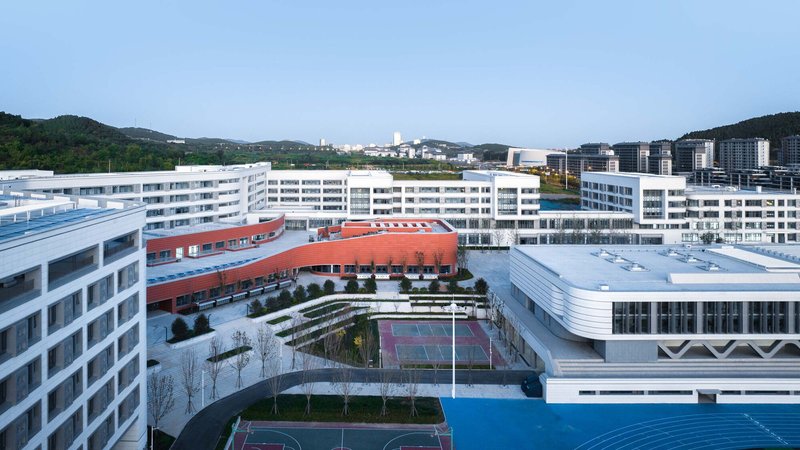 Central courtyard with tennis courts and planted terraces framed by white buildings and red volumes