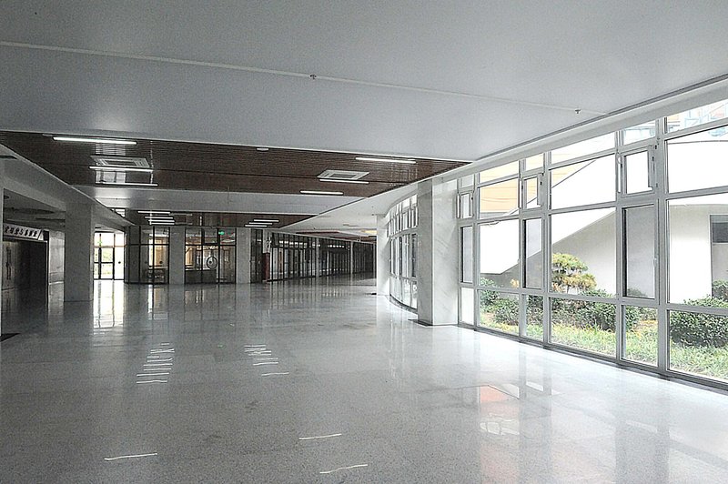 Interior corridor with polished terrazzo flooring and floor-to-ceiling windows overlooking greenery