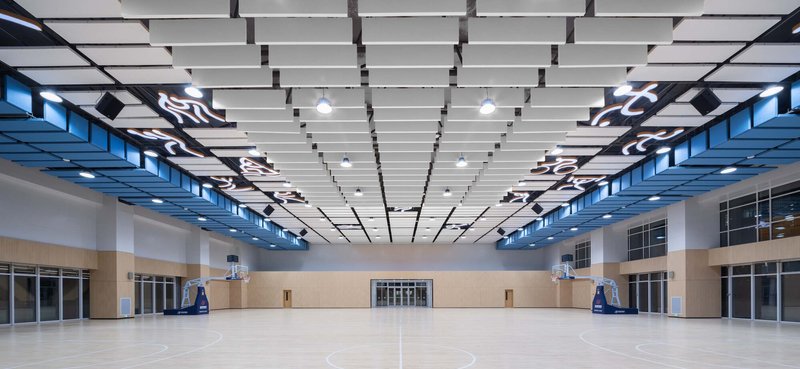 Indoor basketball court with suspended acoustic ceiling panels and high clerestory windows