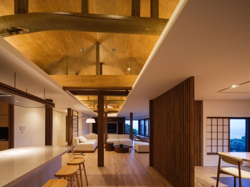 Open-plan living area at dusk with vertical timber screen dividing the space under warm ceiling lighting