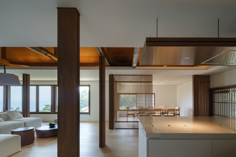 Open-plan interior with dark timber columns, vertical slat screens and an illuminated timber ceiling cove