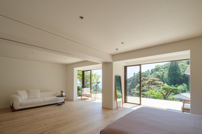 Living room with pale timber flooring and sliding glass doors opening to a sunlit terrace